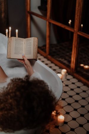 Back view of woman reading a book in bathtub