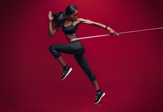 Black female athlete working out with elastic bands in studio