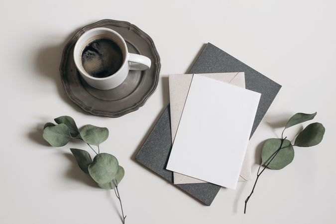 Blank greeting card, invitation mockup, dry eucalyptus tree branches and grey diary with cup of coffee