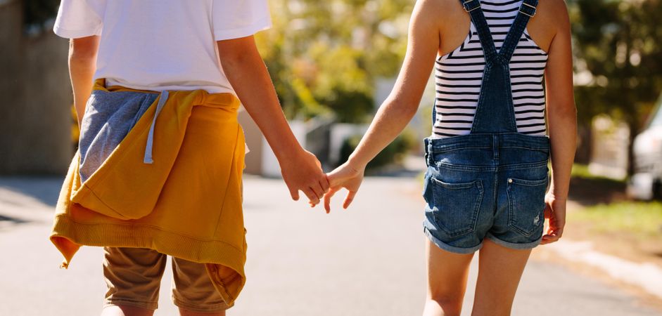 Cropped shot of two kids  walking on an empty street holding hands