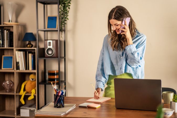 Woman on Phone Call Taking Notes in Home Office - Professional Remote Work