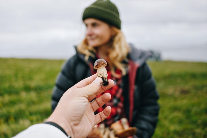 Man holding up foraged mushroom in front of friend