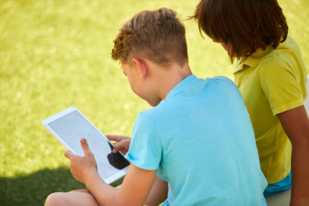 Boys using tablet in garden