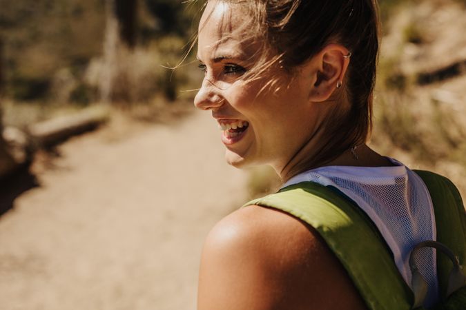Happy young female smiling over her shoulder while on a day hike