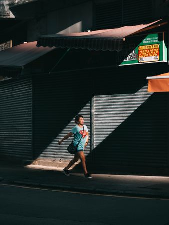 Woman in light t-shirt and blue denim shorts walking on sidewalk