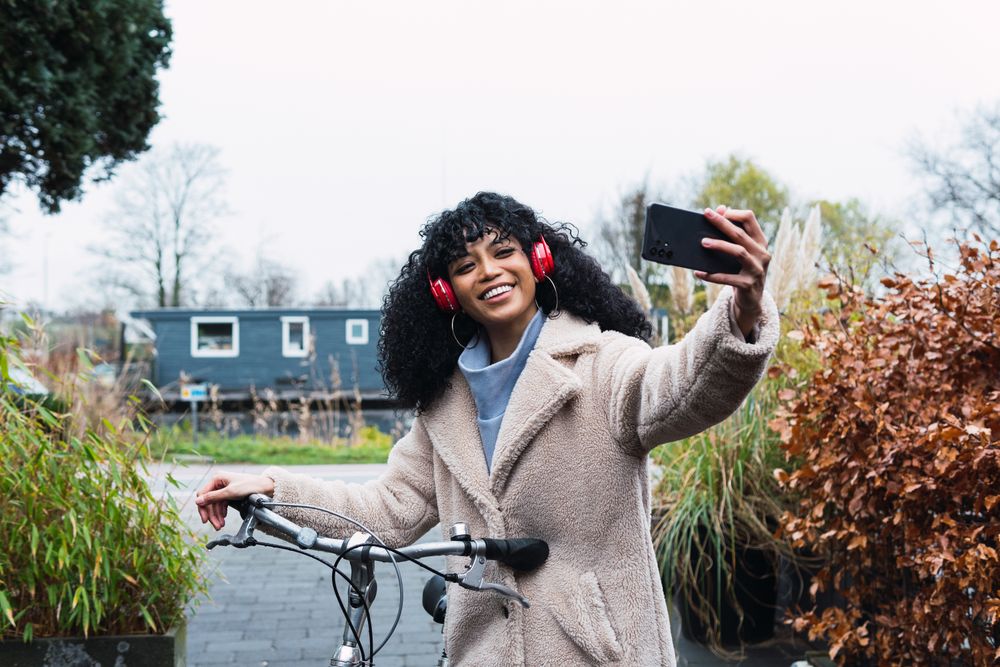 Black woman with smartphone on bicycle