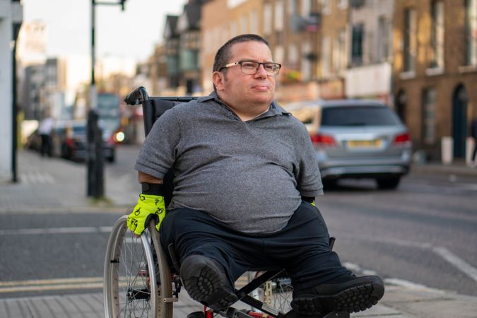 Man in wheelchair on sidewalk in busy city