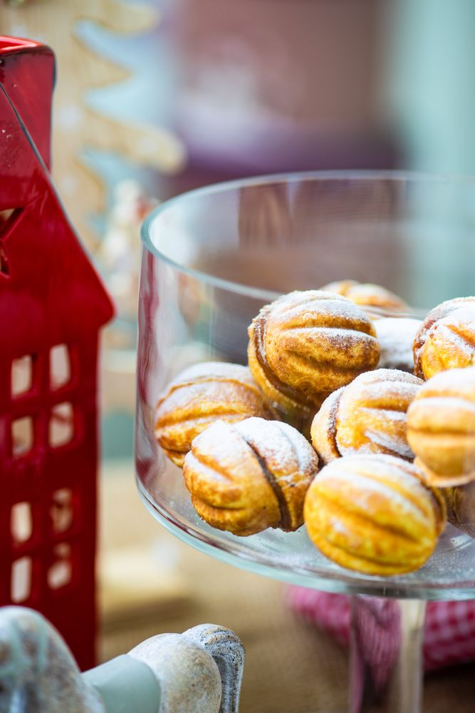 Close up of holiday dessert with walnut shaped cookies stuffed with caramel cream surrounded by decorations