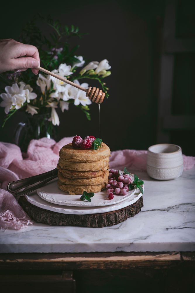 Pile of raspberry pancakes with honey on plate