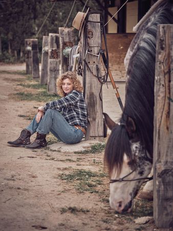Woman sitting at post near horse