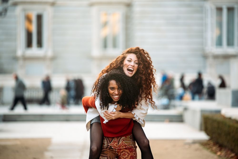 Two cheerful young women playing piggy back