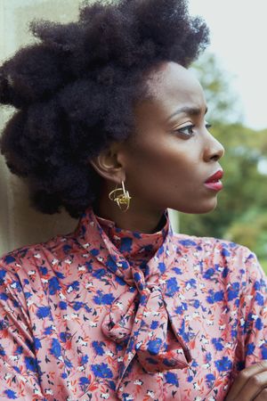 Woman in blue and pink floral button up shirt wearing gold pendant earrings