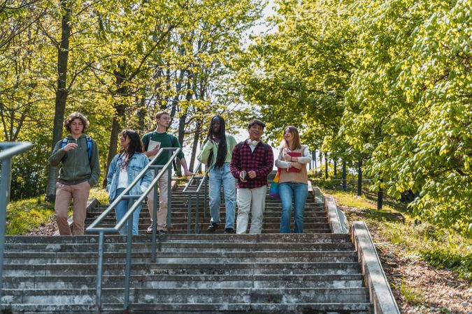 Group of multi-ethnic students walking down tree lined outdoor stairs