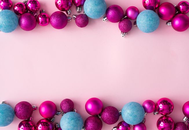 Pink and blue festive baubles bordering pink background