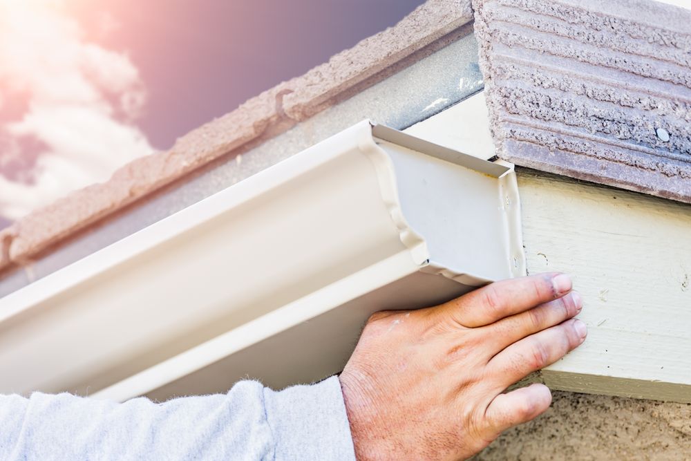 Worker Attaching Aluminum Rain Gutter to Fascia of House