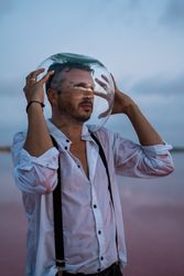 Man with fish tank on head standing at seashore