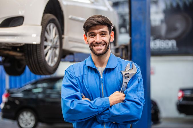 Portrait of automotive mechanic man holding wrench