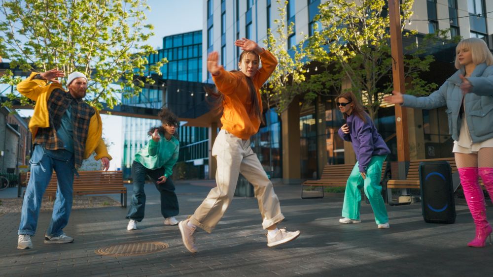 Vibrant Outdoor Scene Capturing A Diverse Group Of Young Adults Joyfully Dancing
