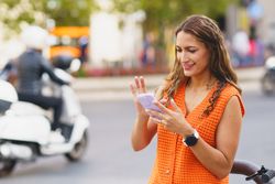 Latina woman scrolling the mobile in the street