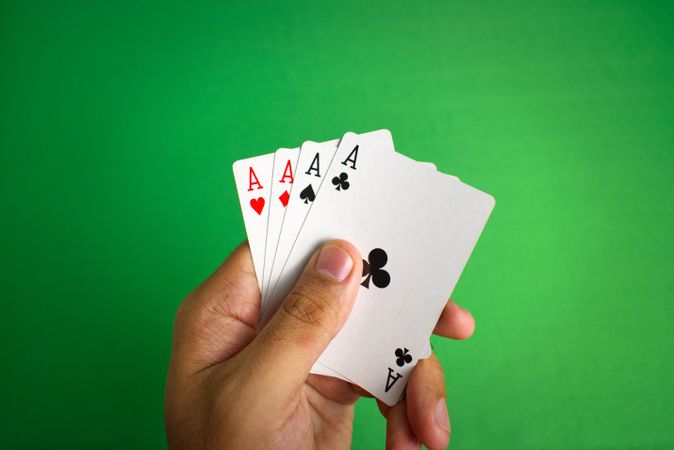 adult hand holding aces poker cards