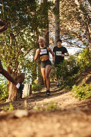 Woman runner running on mountain trail with at male athlete behind her