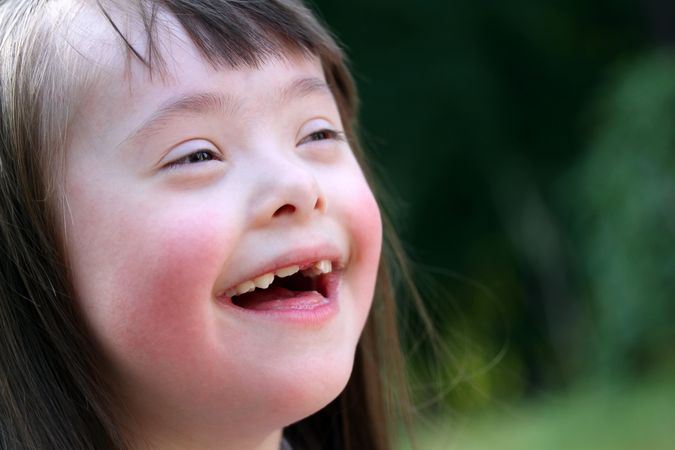 Girl with Down syndrome smiling outside