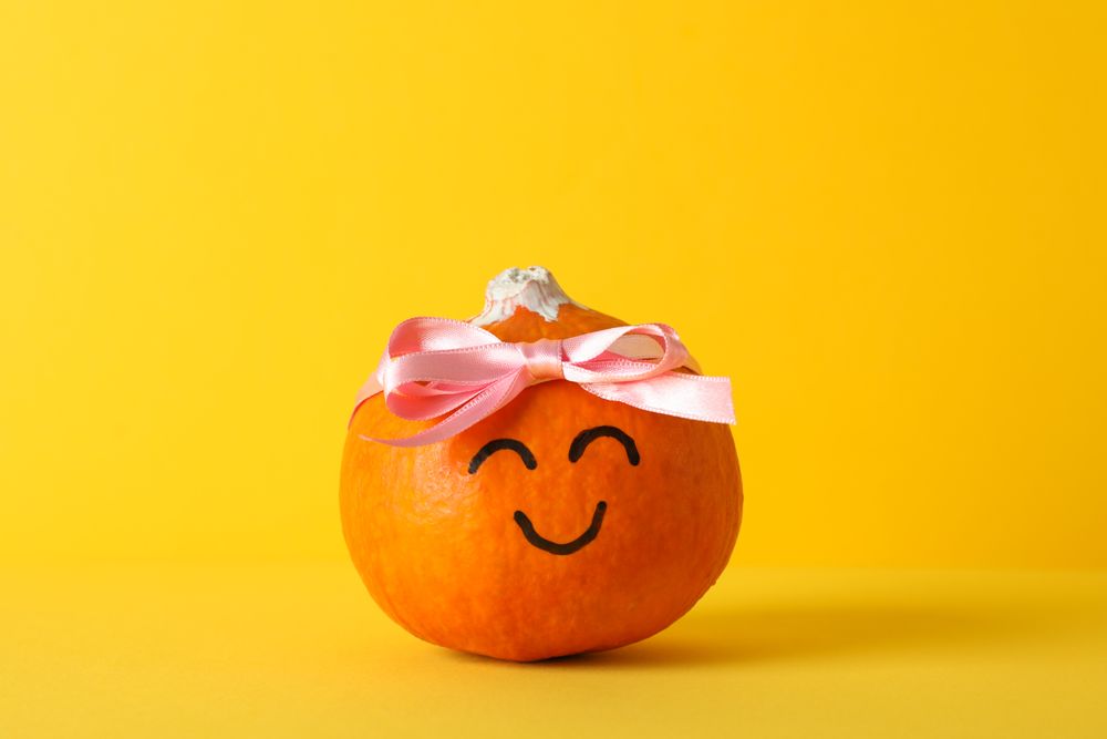 Happy pumpkin with bow on yellow background, space for text