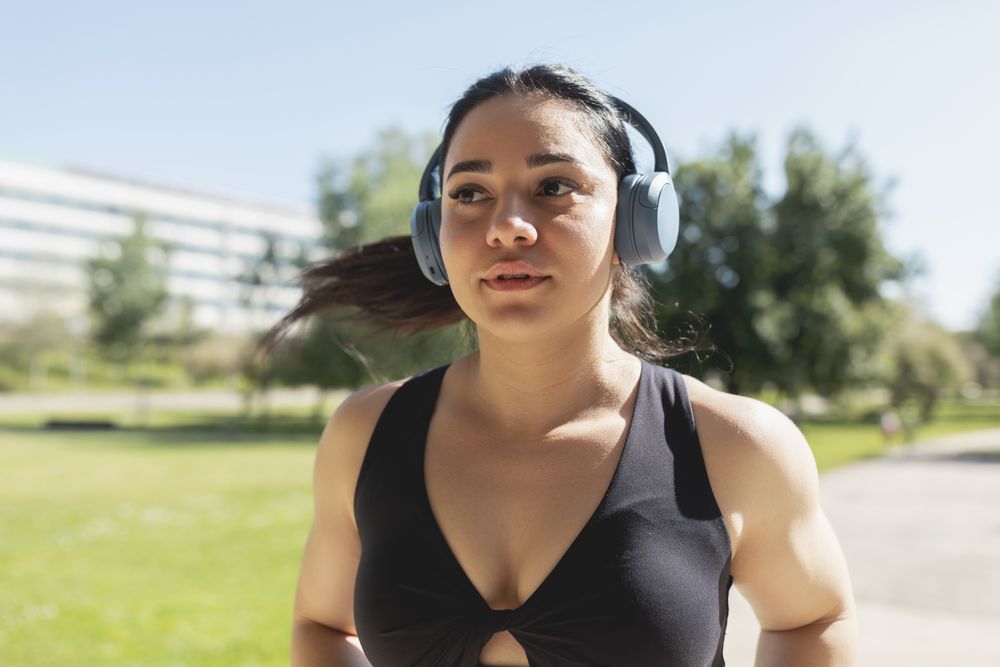 A young woman listening to music with headphones, while she is running and training, Zaragoza, Spain