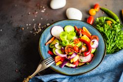 Delicious healthy raw vegetable salad served on blue plate