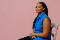 Thoughtful female with bandage after immunization in pink studio shoot, copy space