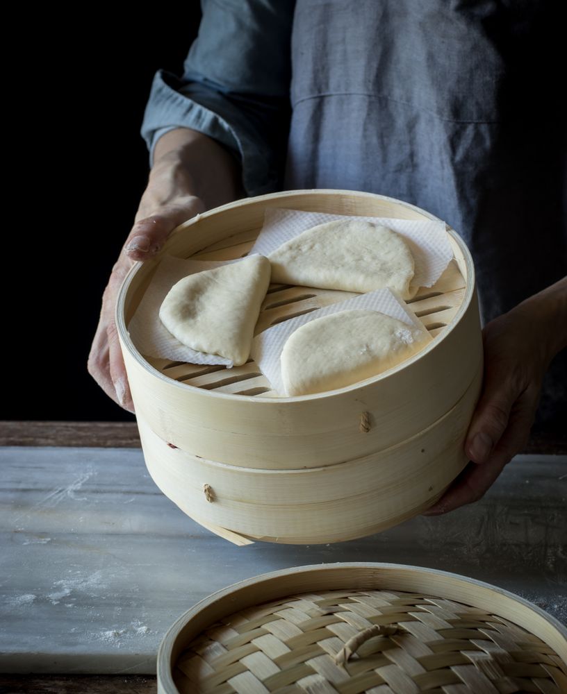 Cook preparing buns in bamboo steamer