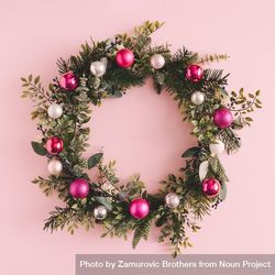 Christmas wreath made of decorative baubles and branches on pink background 0JgNl5