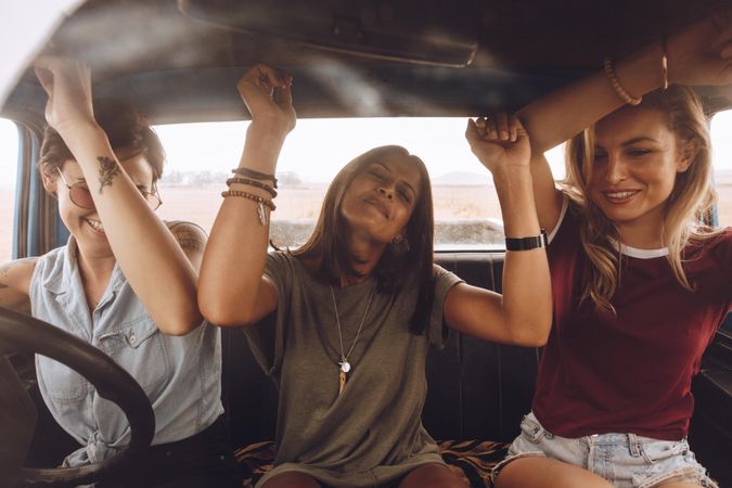 Three female friends enjoying traveling in the car