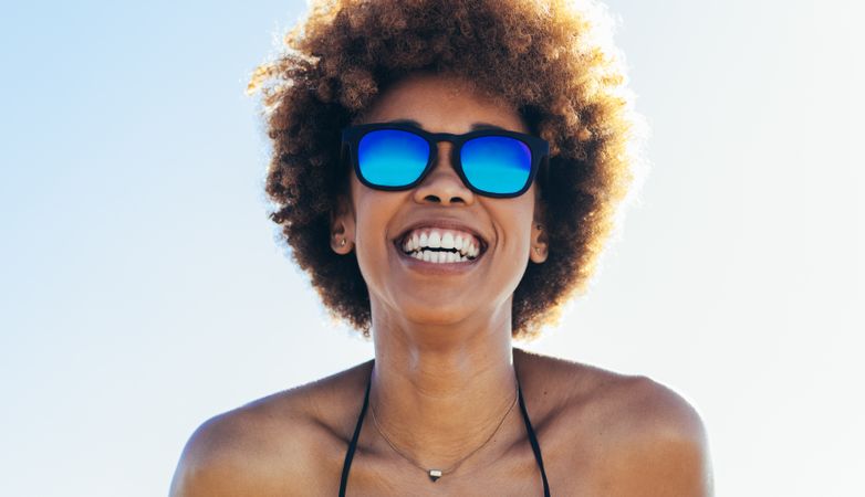 Close up of woman in bikini and sunglasses looking at camera
