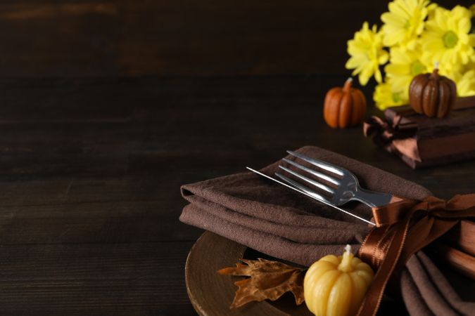 Cutlery, pumpkins and flowers on wooden background, space for text