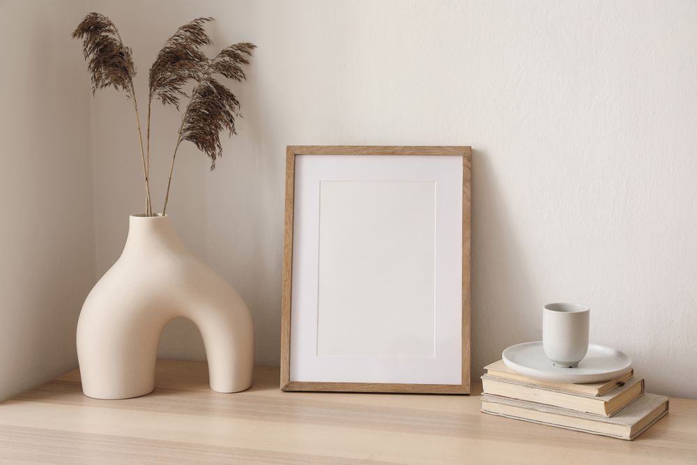 Table with modernist vase and decorative reeds, and mock up poster