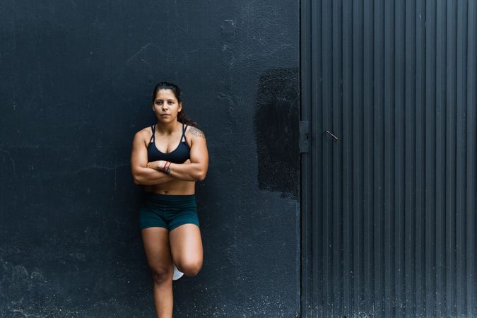 Hispanic sportswoman standing near wall