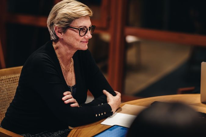 Successful older woman sitting at a meeting with colleagues in boardroom