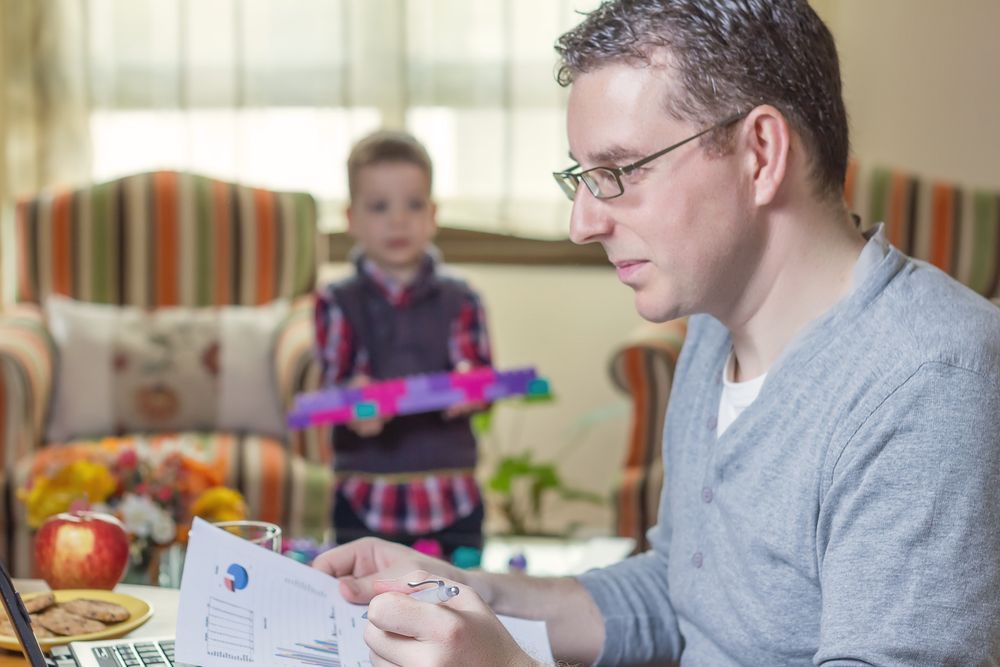 Father working in home office and son playing