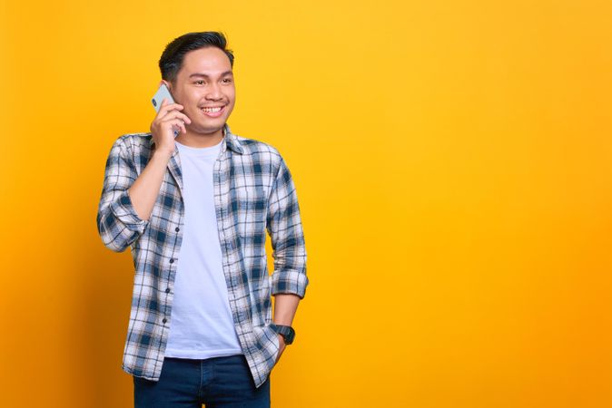 Happy Asian male talking on his smart phone in studio shoot