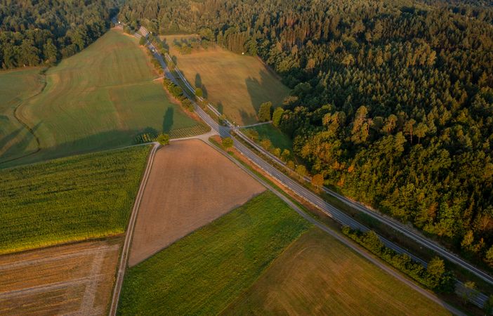 Morning scenery, aerial view, with road passing between forest and agricultural fields