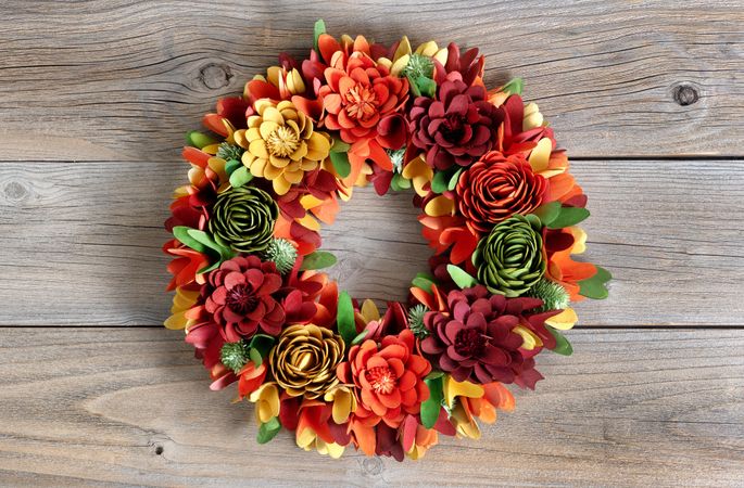 Colorful wreath made of wooden flowers and leaves on vintage wood