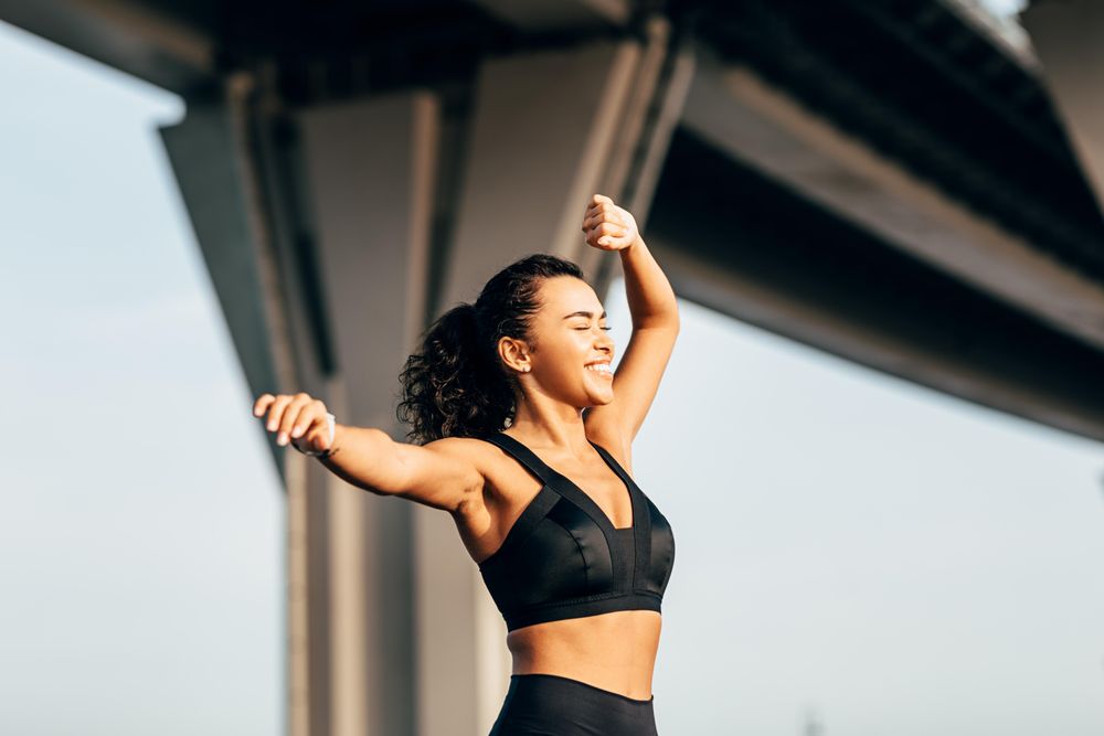 Smiling female stretching arm outdoors