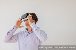 Happy young man using the virtual reality headset against grey background with copy space 4Nk29b
