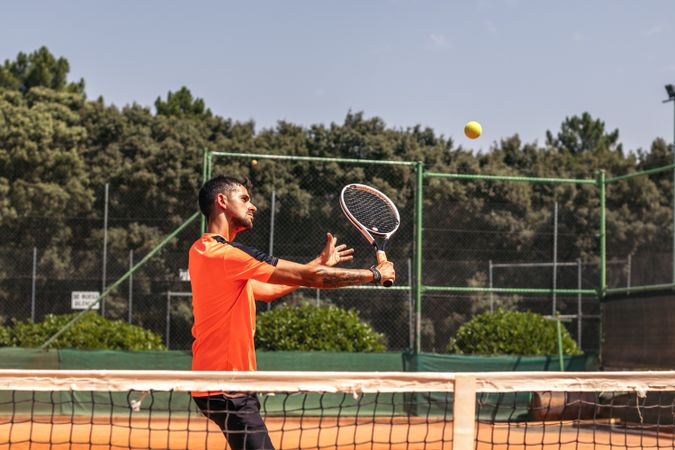 Man in sportswear playing tennis on a dirt tennis court