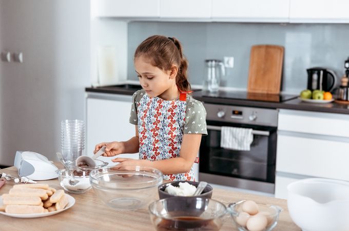 Girl making tiramisu dessert in kitchen
