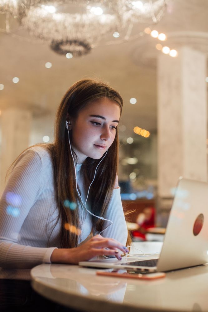 Woman in a restaurant working on her laptop with earbuds