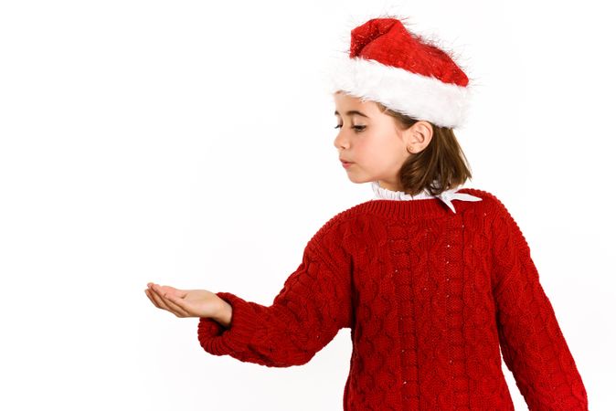 Female child in Christmas outfit with hand up to copy space