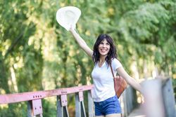 Carefree woman standing on foot bridge in forest