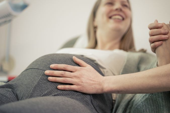 Close-up of a couple's hands on a pregnant belly.